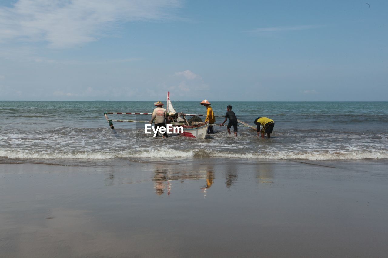 Fisherman standing by sea against sky