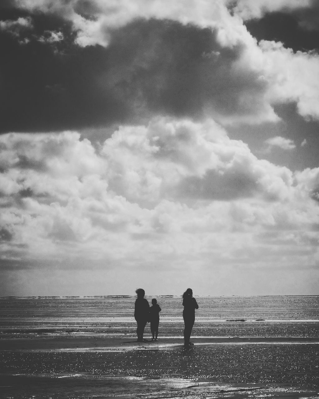 SILHOUETTE COUPLE STANDING ON BEACH AGAINST SKY