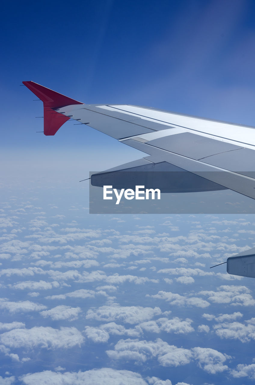 Window view of blue sky and fluffy clouds from passenger seat on airplane. concept of travel