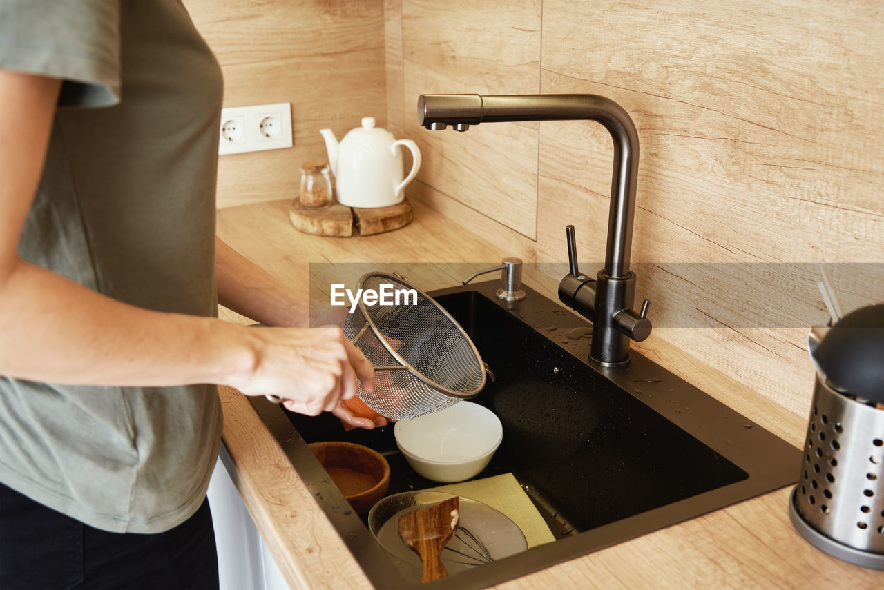Woman waching dishes in kitchen sink