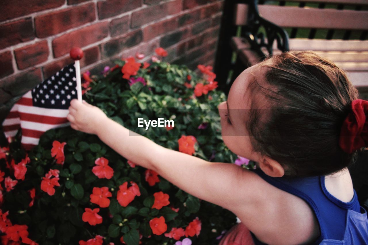 Close-up of girl holding american flag by plants