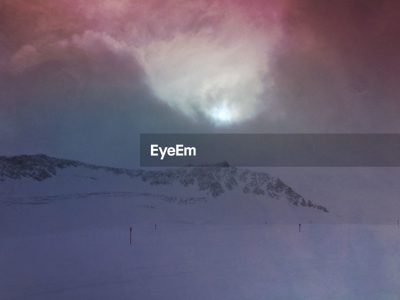 Scenic view of snowcapped mountains against cloudy sky during sunset