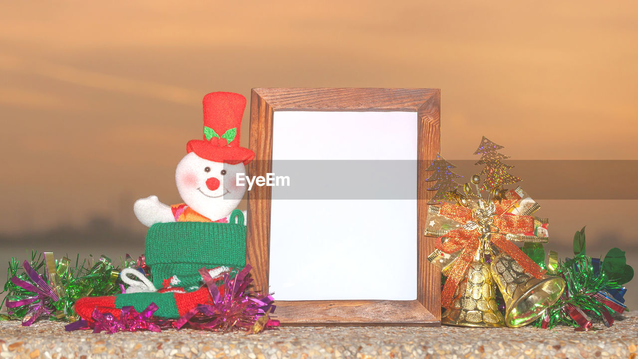 Close-up of blank picture frame with christmas decorations on table