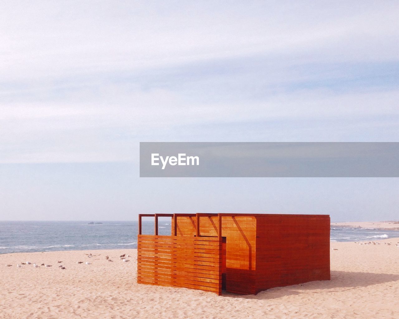 Wooden built structure at sandy beach against sky