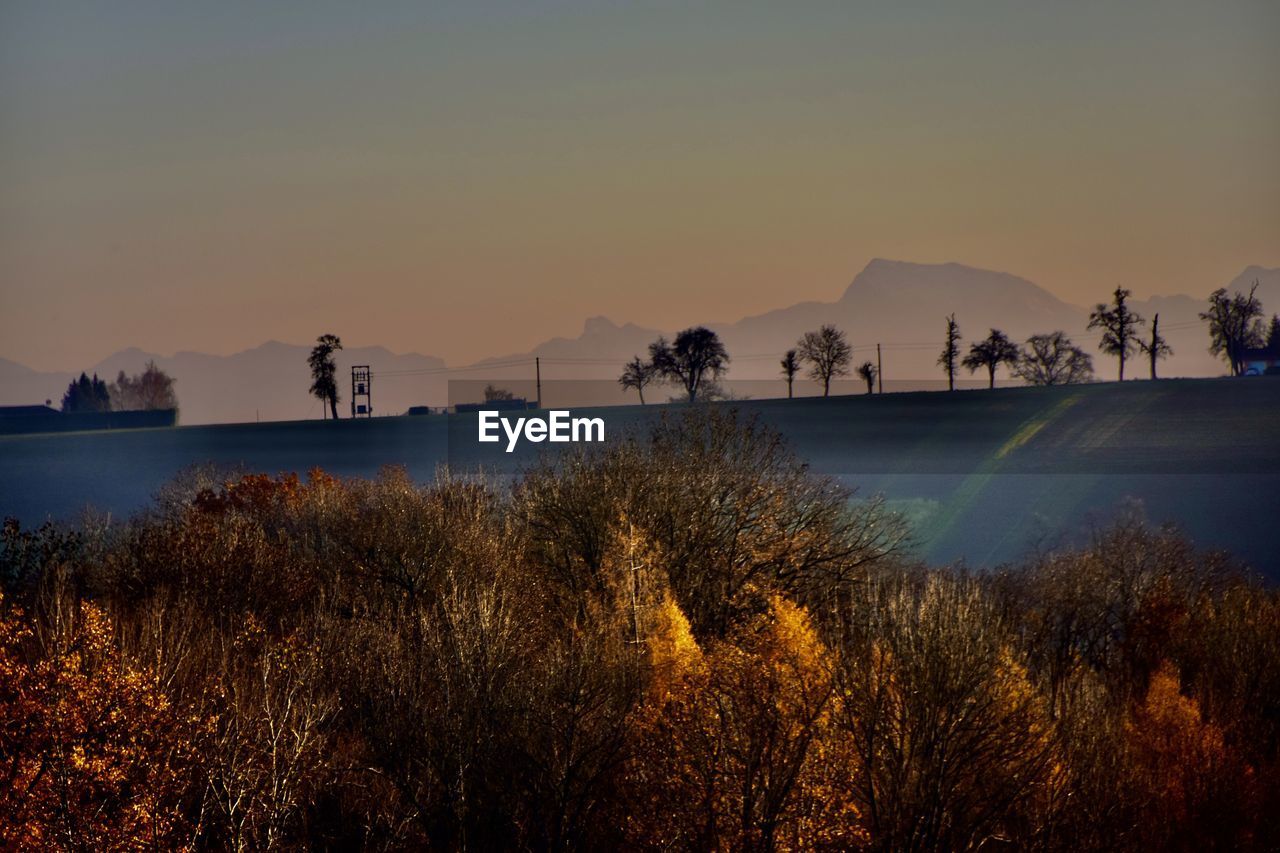 Scenic view of trees against mountains and sky during sunset