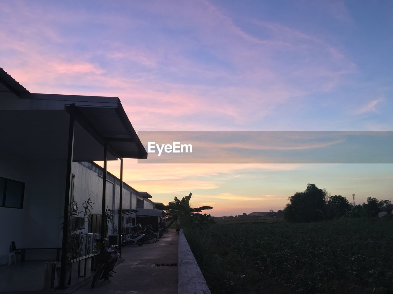 HOUSES BY ROAD AGAINST SKY DURING SUNSET