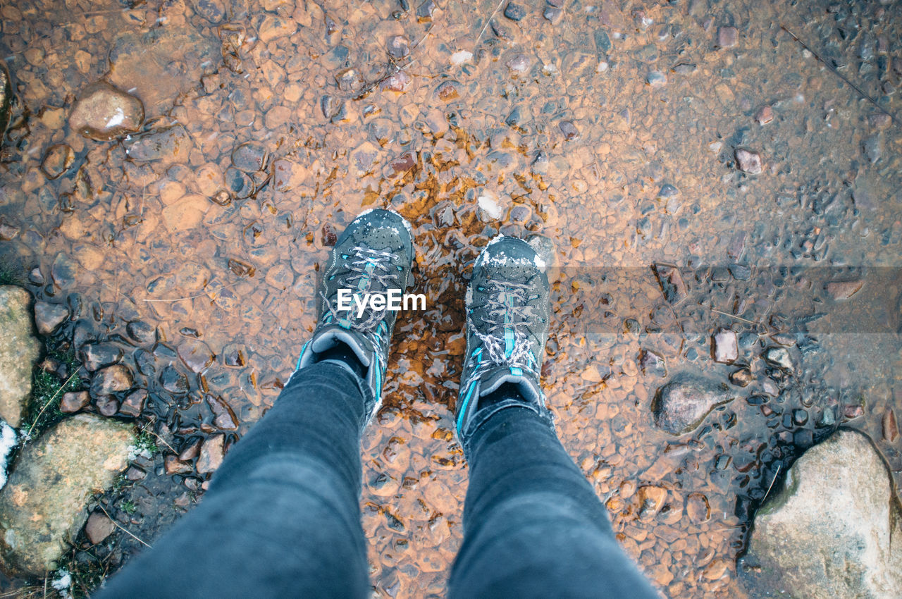 Low section of man standing on stream