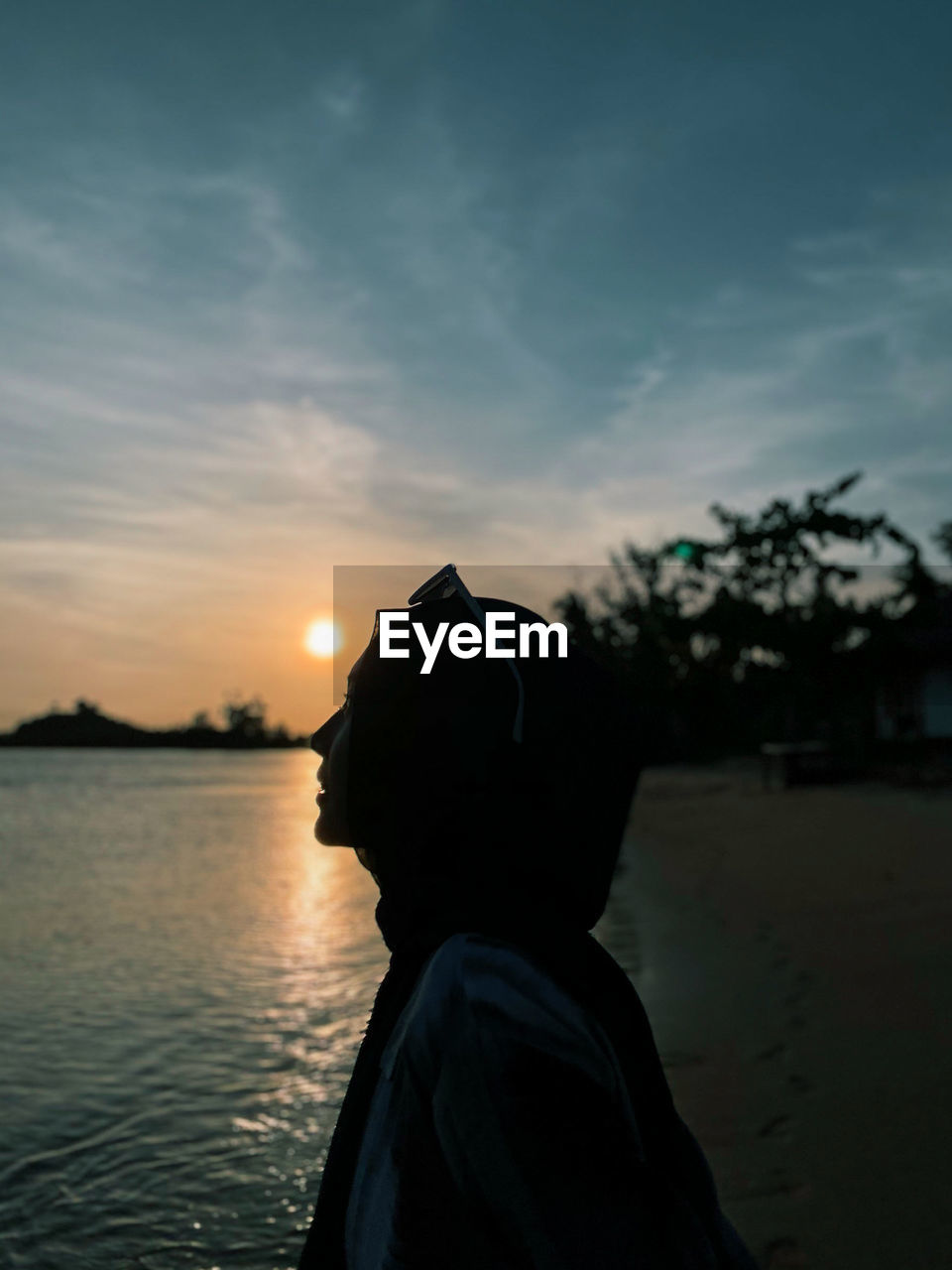 A beautiful woman smiling in front of sunset at beach