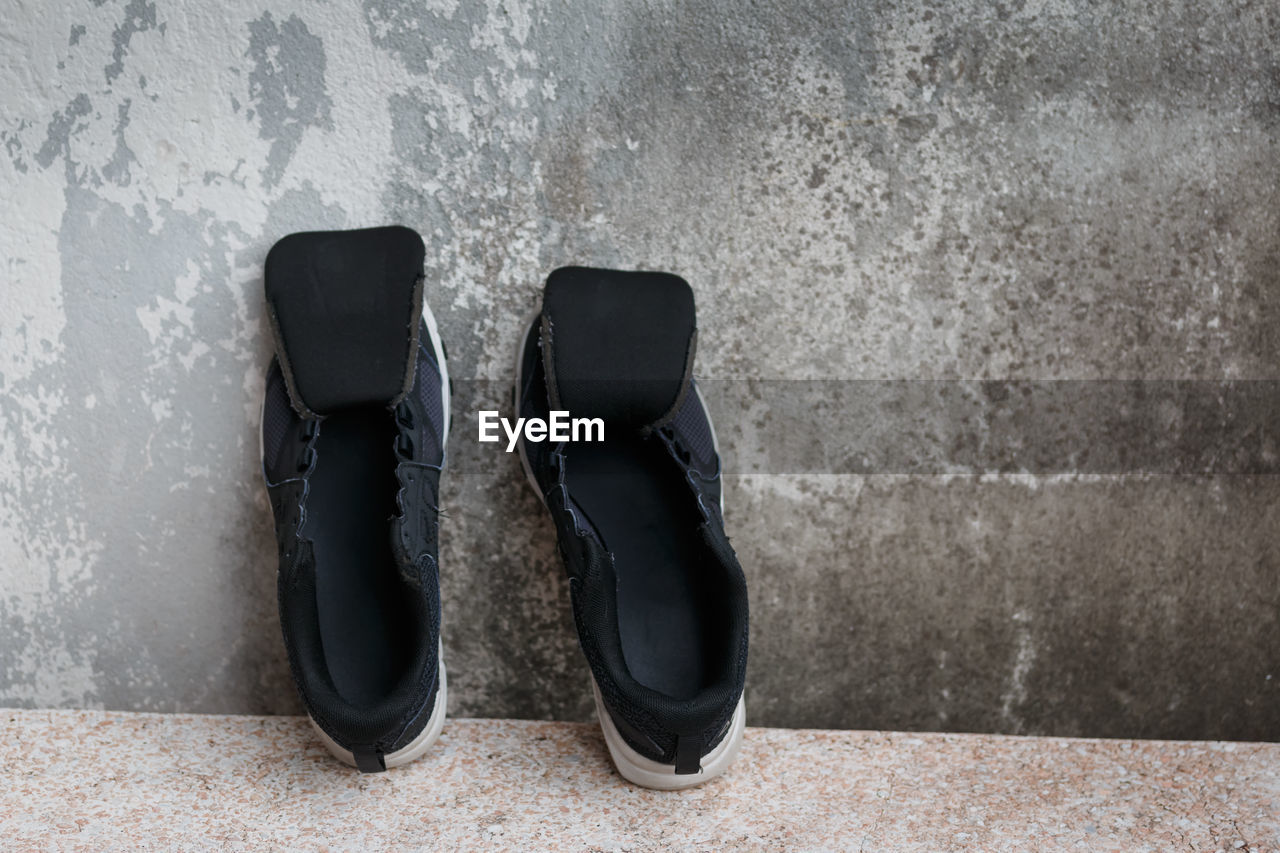 CLOSE-UP OF SHOES ON FLOOR AGAINST WALL