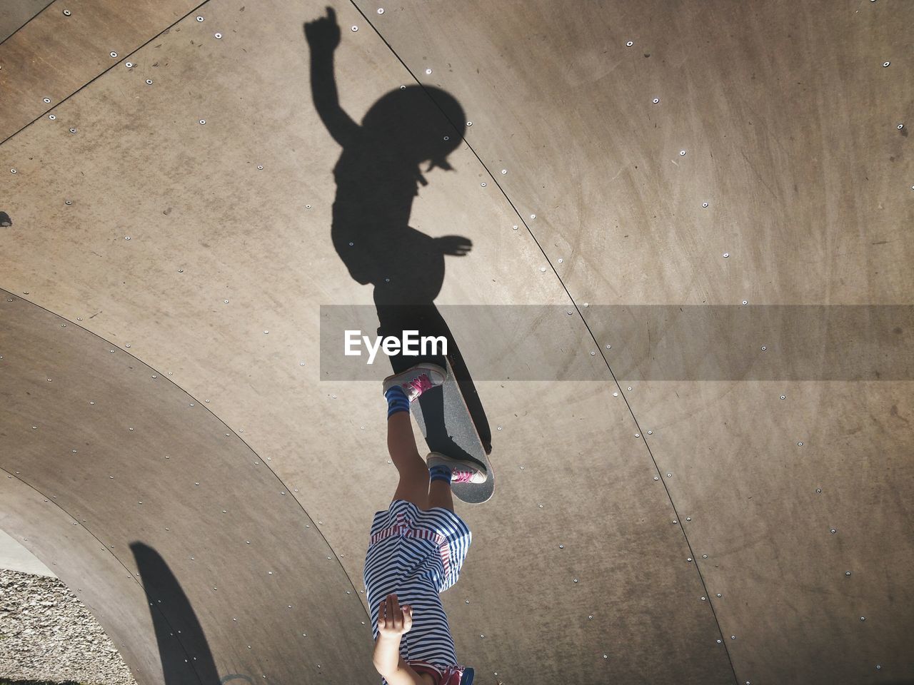 Low section of girl performing stunt at skateboard park