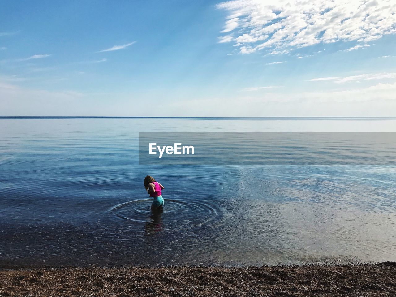 Girl standing in sea against blue sky