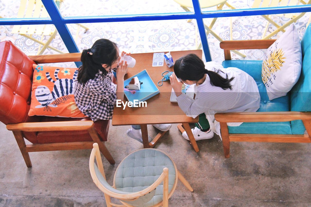 High angle view of friends having drinks while sitting in cafe
