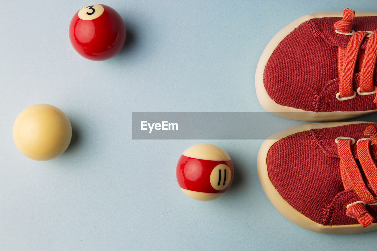 Directly above shot of canvas shoes with pool balls on blue background