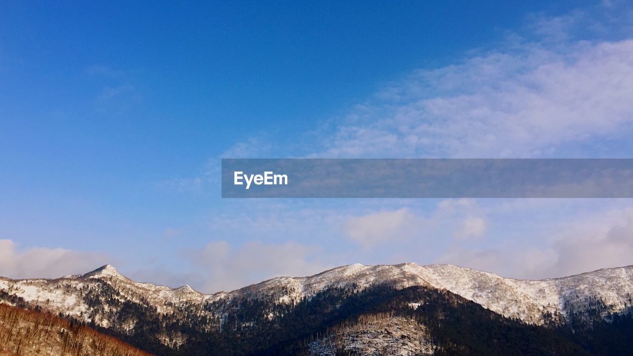 Scenic view of snowcapped mountains against blue sky