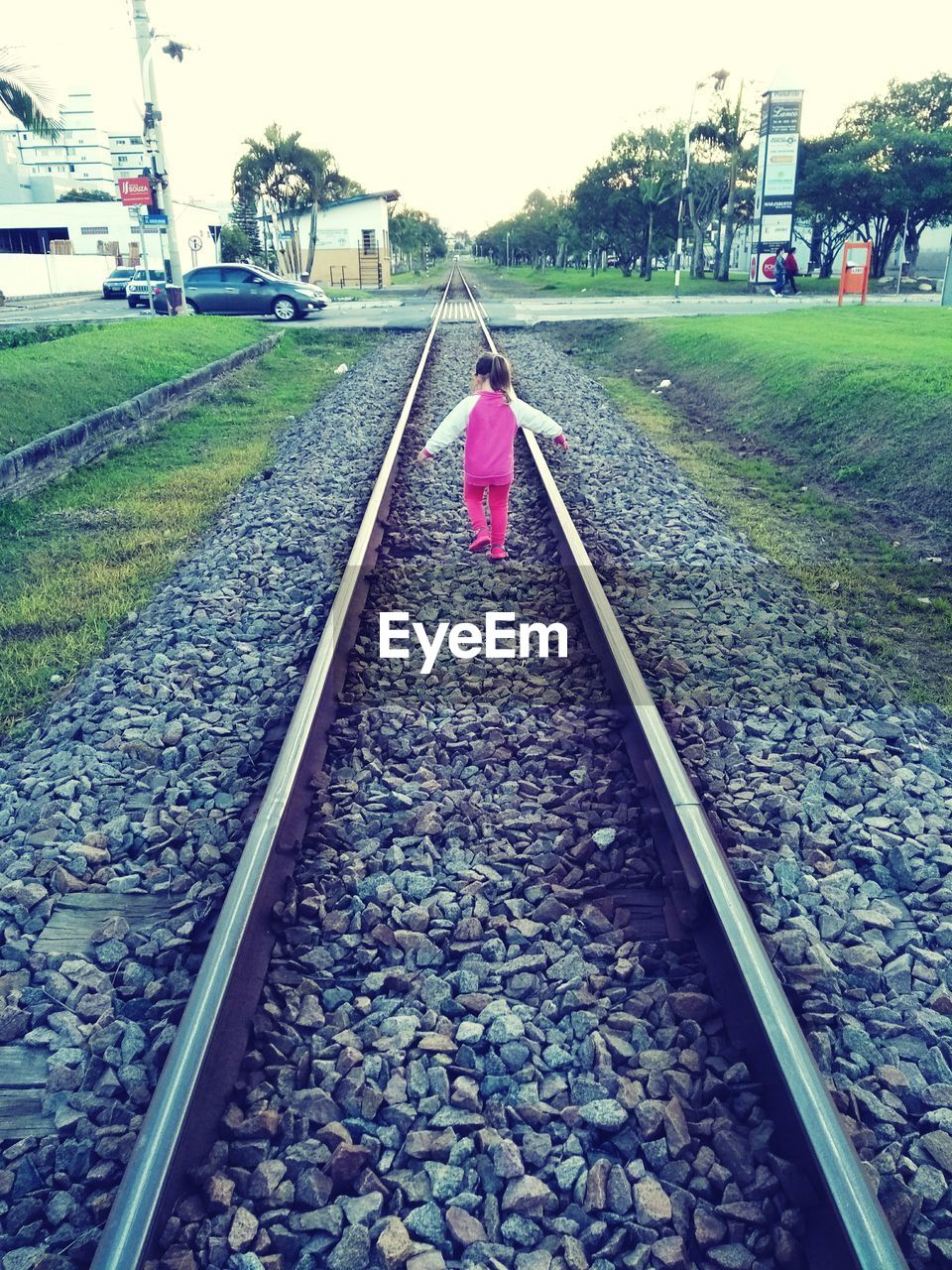 REAR VIEW OF WOMAN ON RAILROAD TRACKS