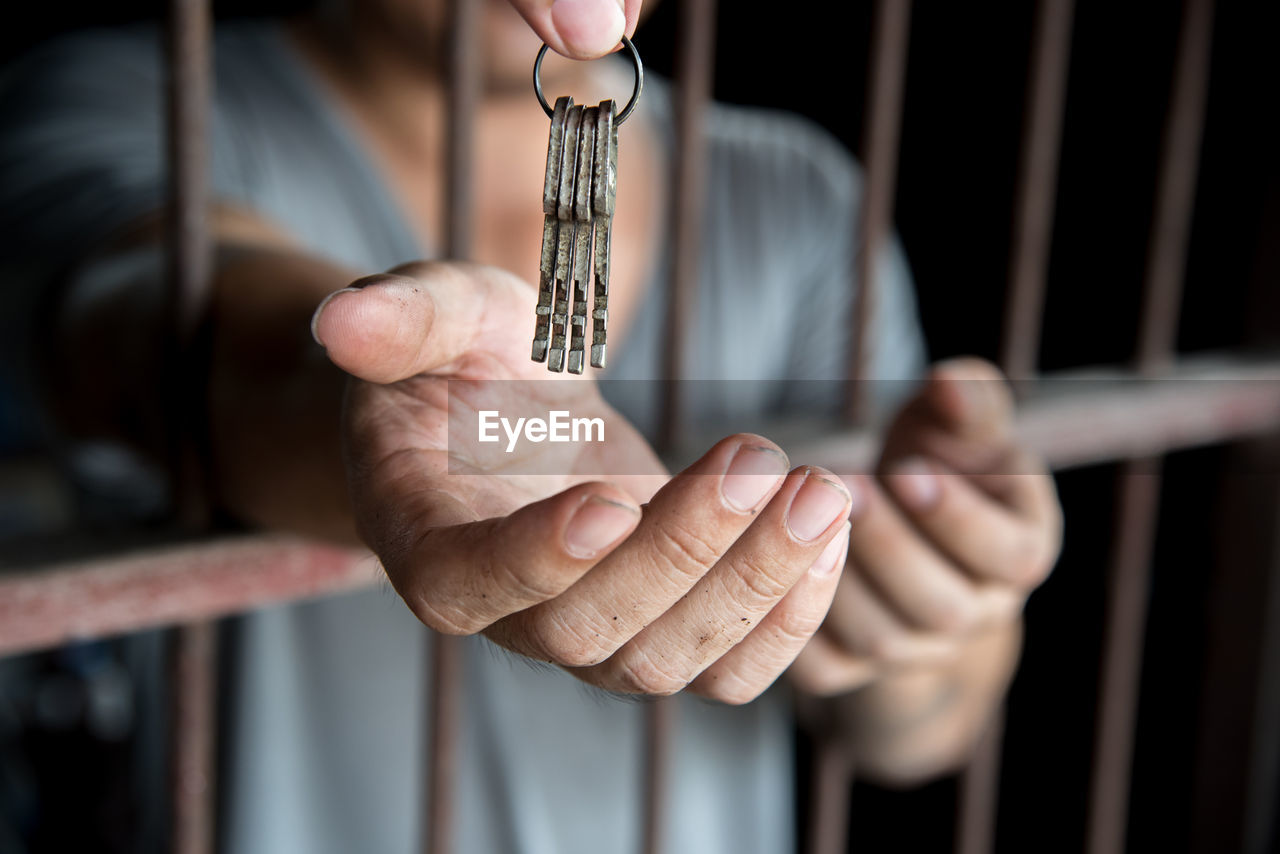Cropped hand giving prisoner keys in prison cell