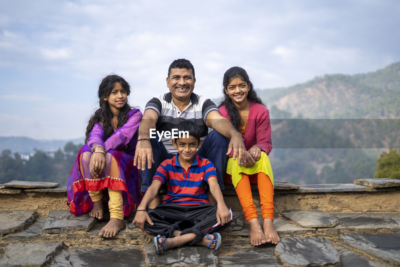 Indian father sitting with his kids smiling while looking into the camera. happy family concept.
