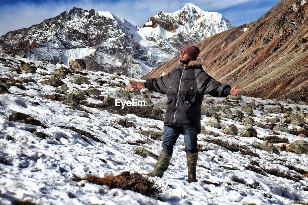 Man standing on rock against snowcapped mountains