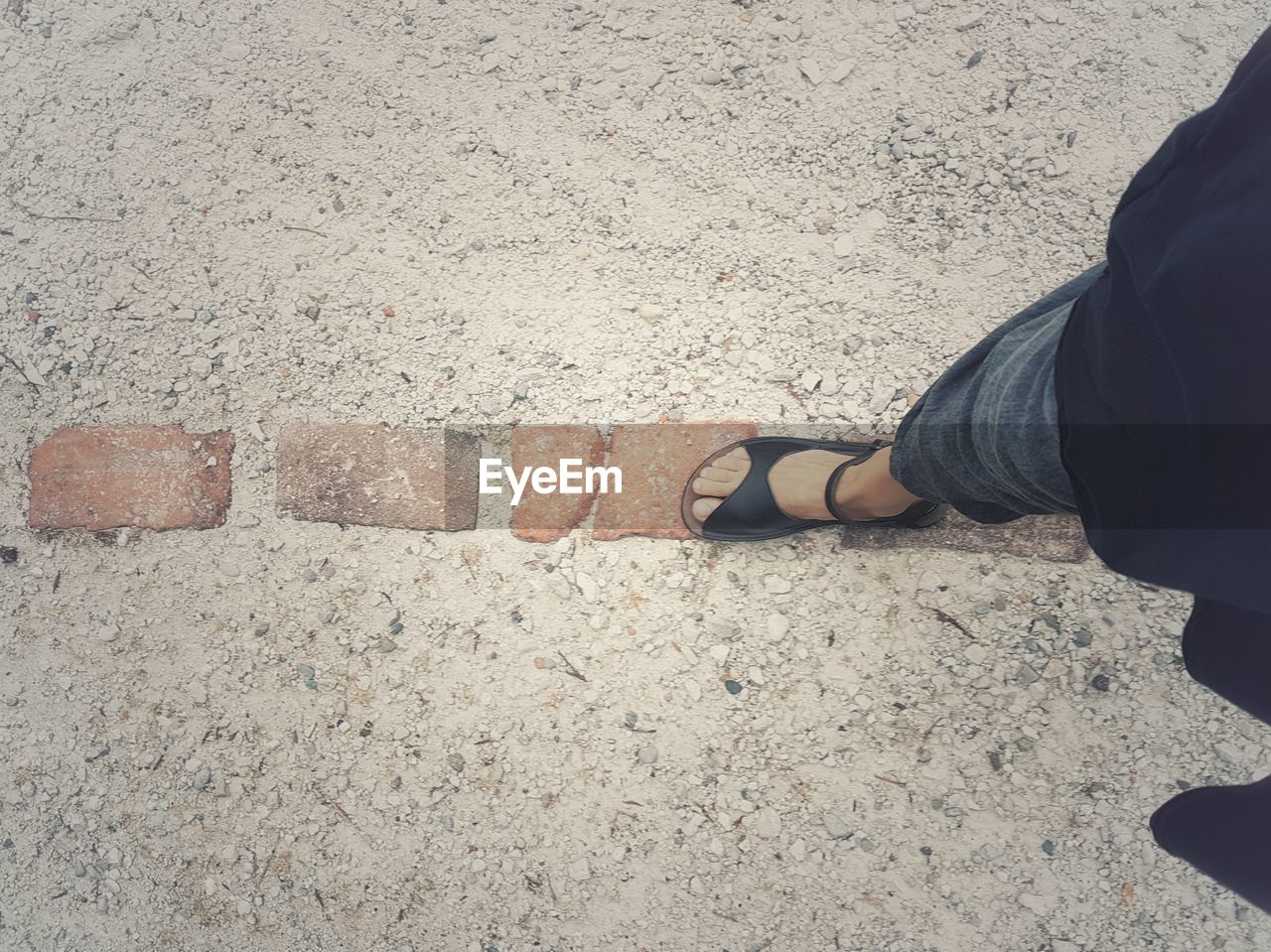 LOW SECTION OF MAN STANDING ON CONCRETE FOOTPATH