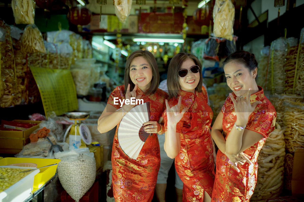 Portrait of smiling women in traditional clothing gesturing at store