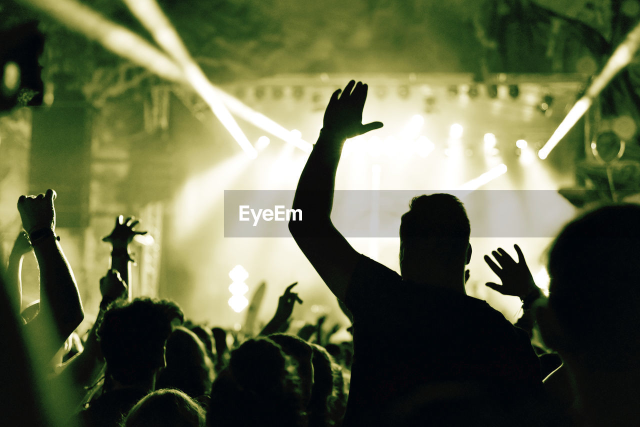 Crowd at a music concert with raising hands up, toned image