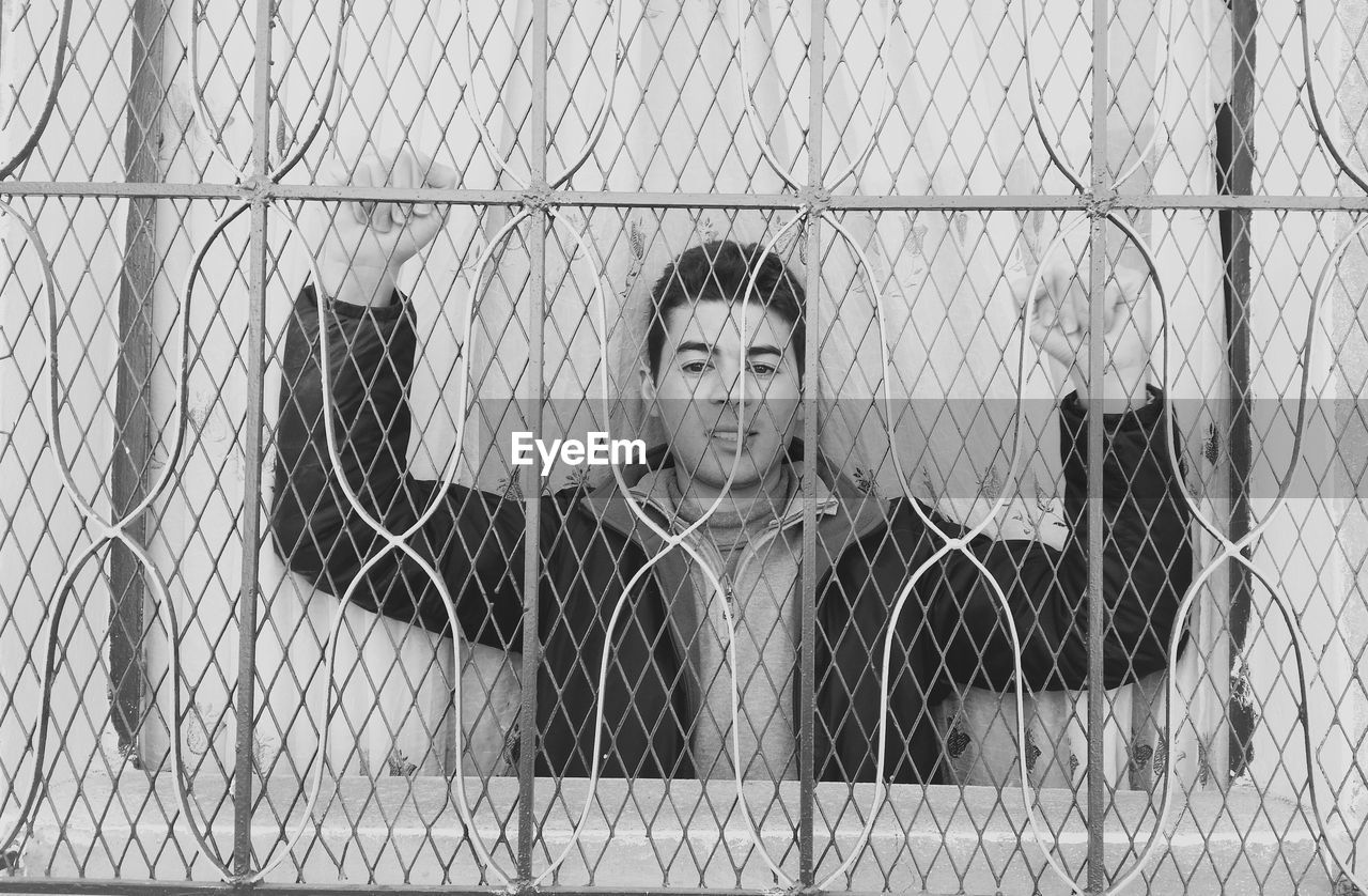 Portrait of man seen through fence