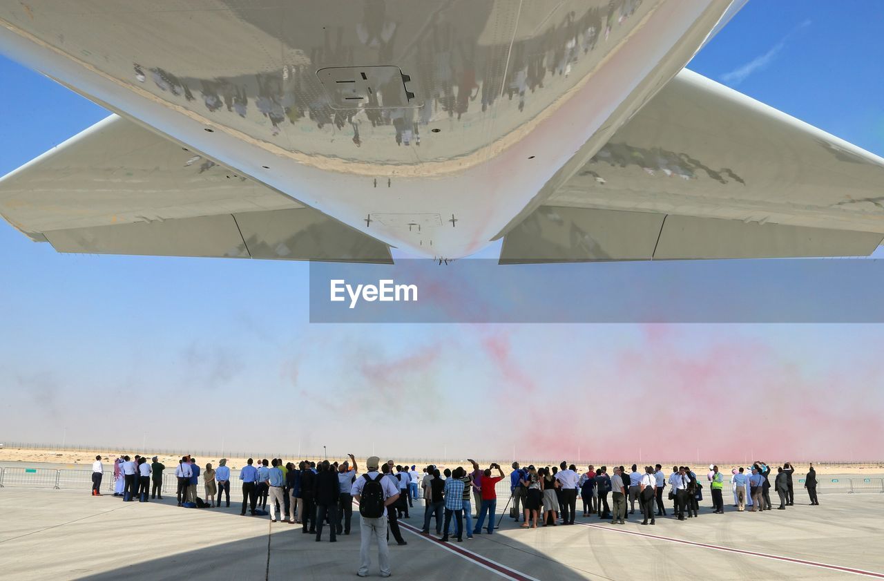 People watching airplane at airshow against sky