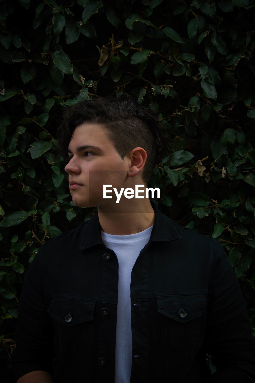 Young man looking away while standing outdoors