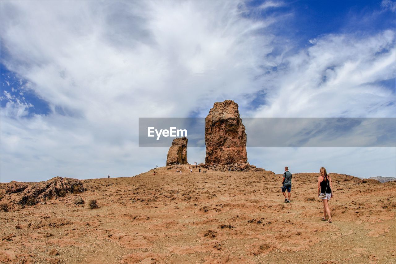 People walking on landscape against sky