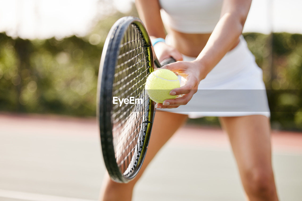 midsection of woman playing tennis at court