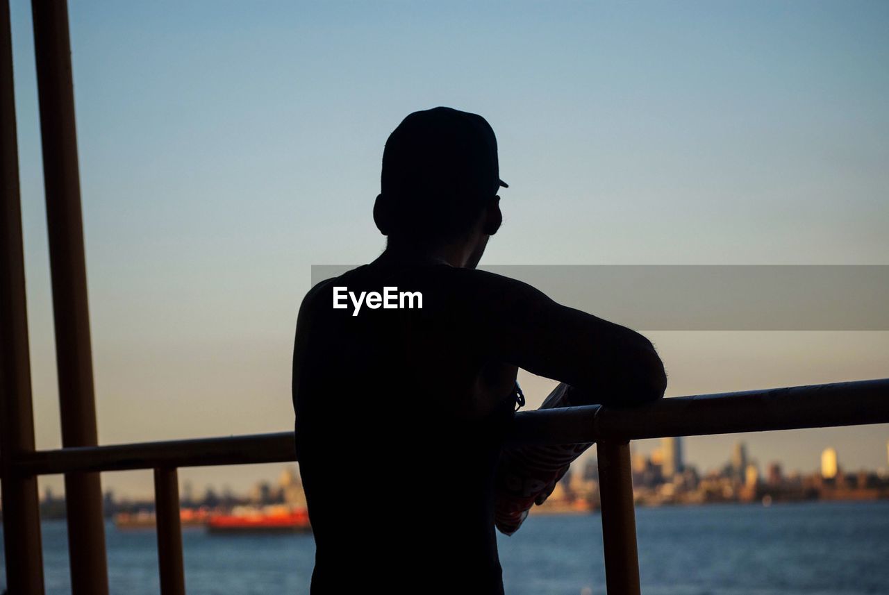 Rear view of silhouette man looking at sea against sky