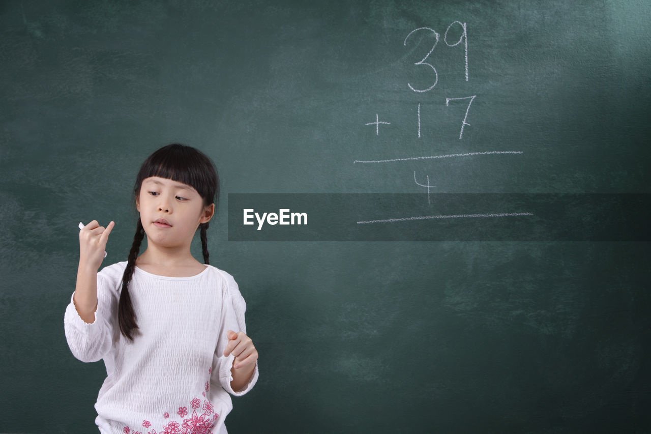 Girl learning mathematics on blackboard