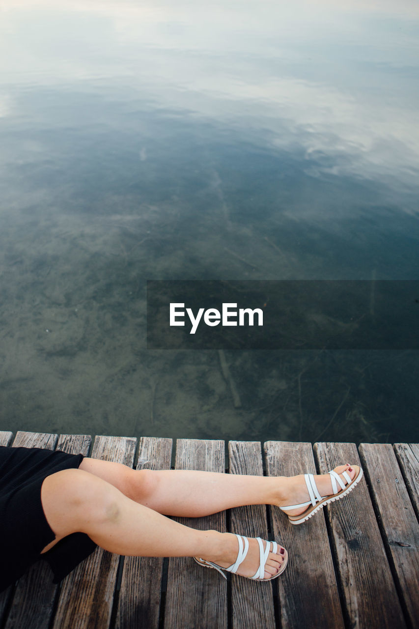 Young woman lying on pier by lake