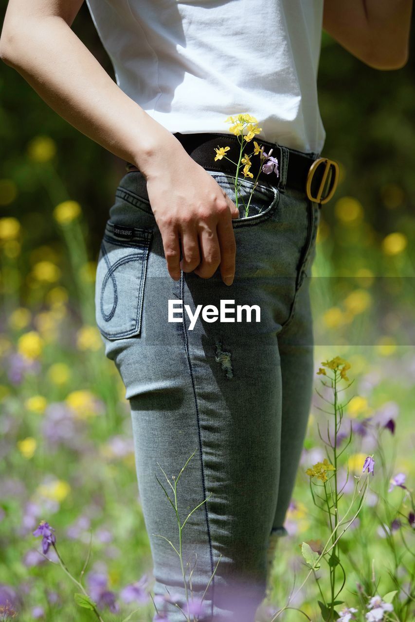 Midsection of woman standing by flowering plants