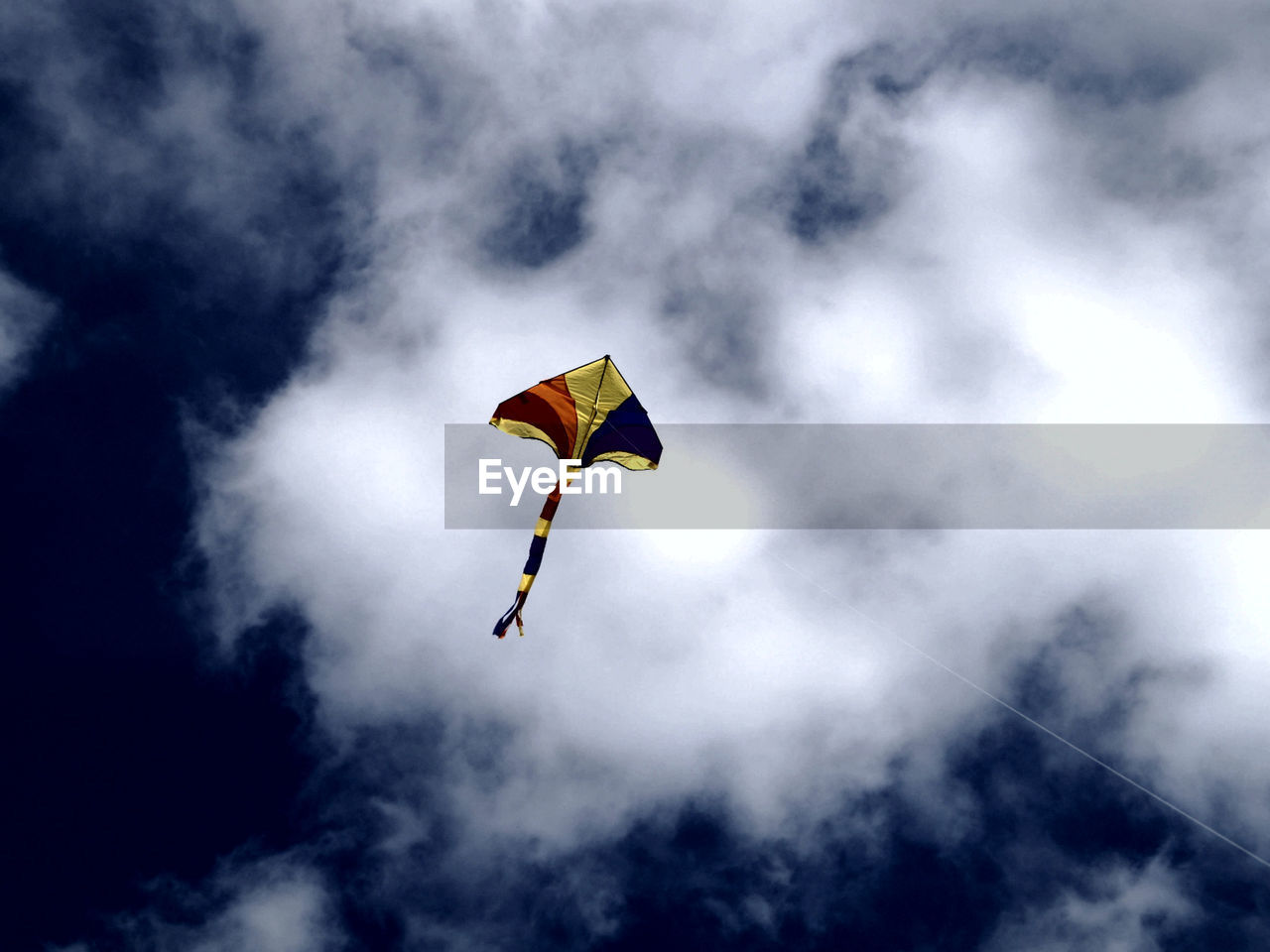 Low angle view of kite flying against cloudy sky