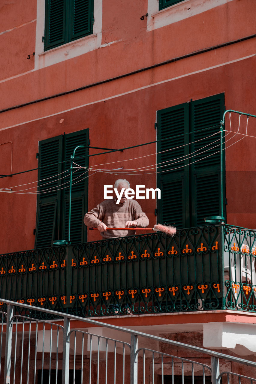 PORTRAIT OF MAN ON BUILDING TERRACE AGAINST BRICK WALL