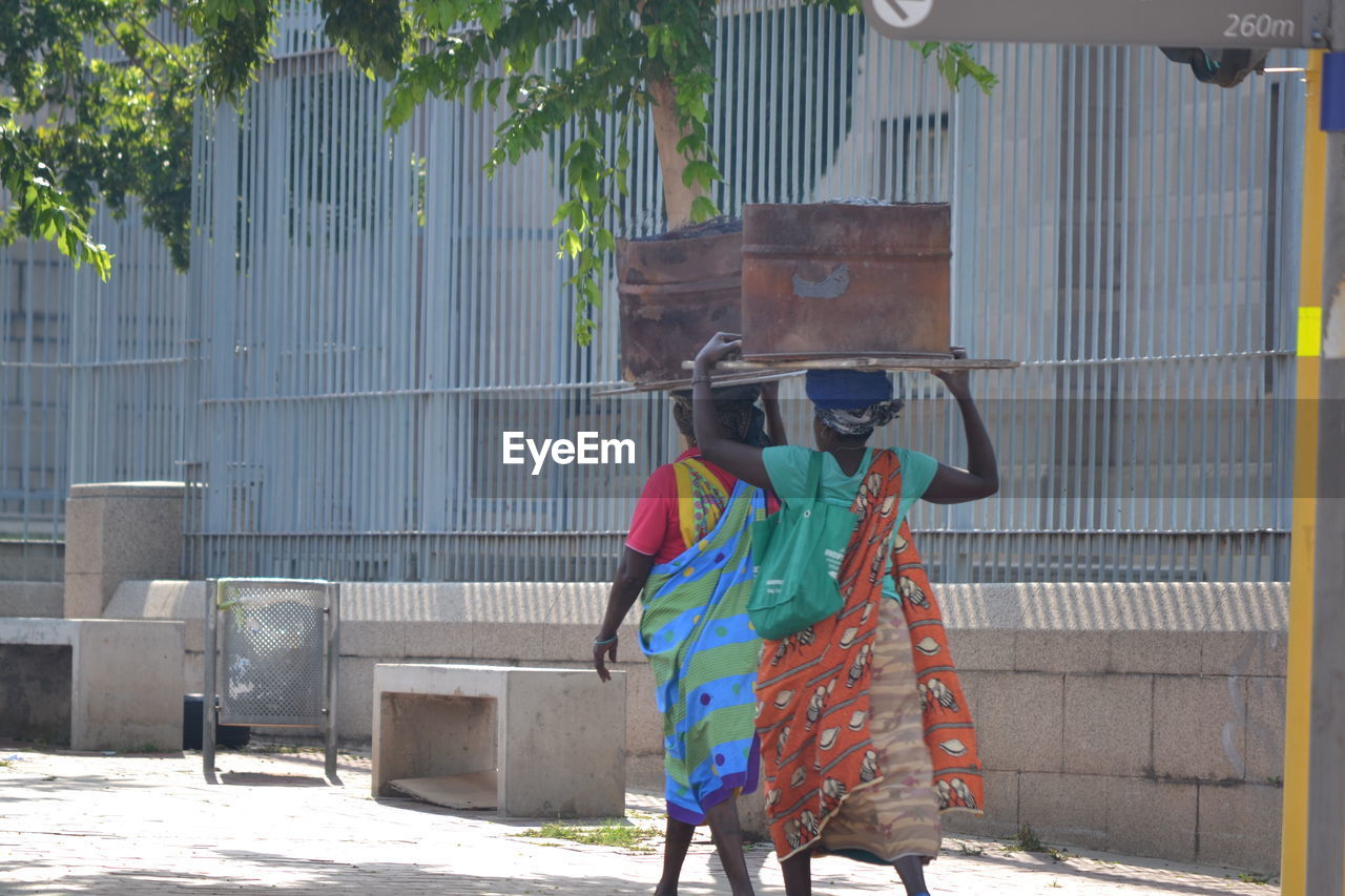 FULL LENGTH REAR VIEW OF WOMAN STANDING ON STREET