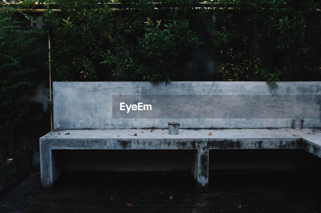 Small garbage bins on bench against trees