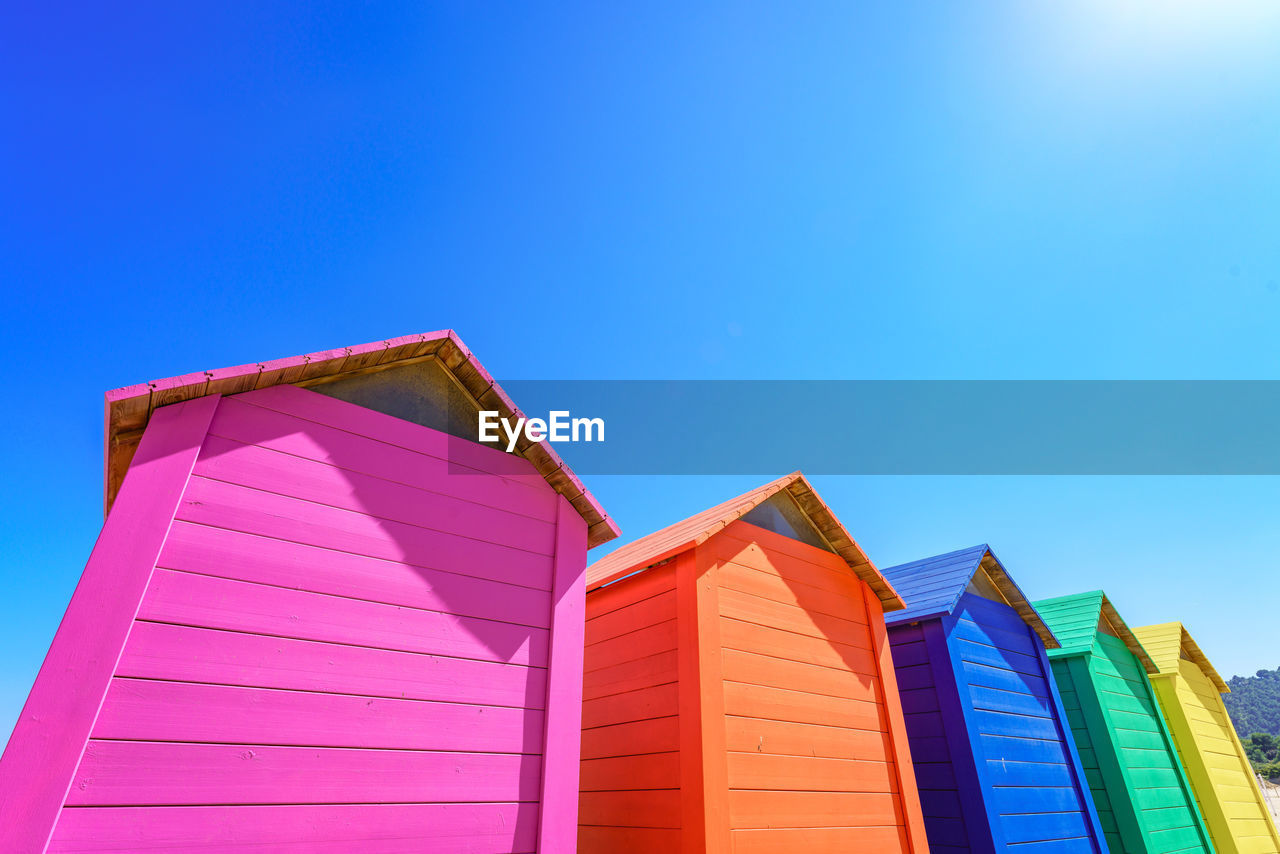 Vibrant colourful wooden huts against clear blue sky with copy space