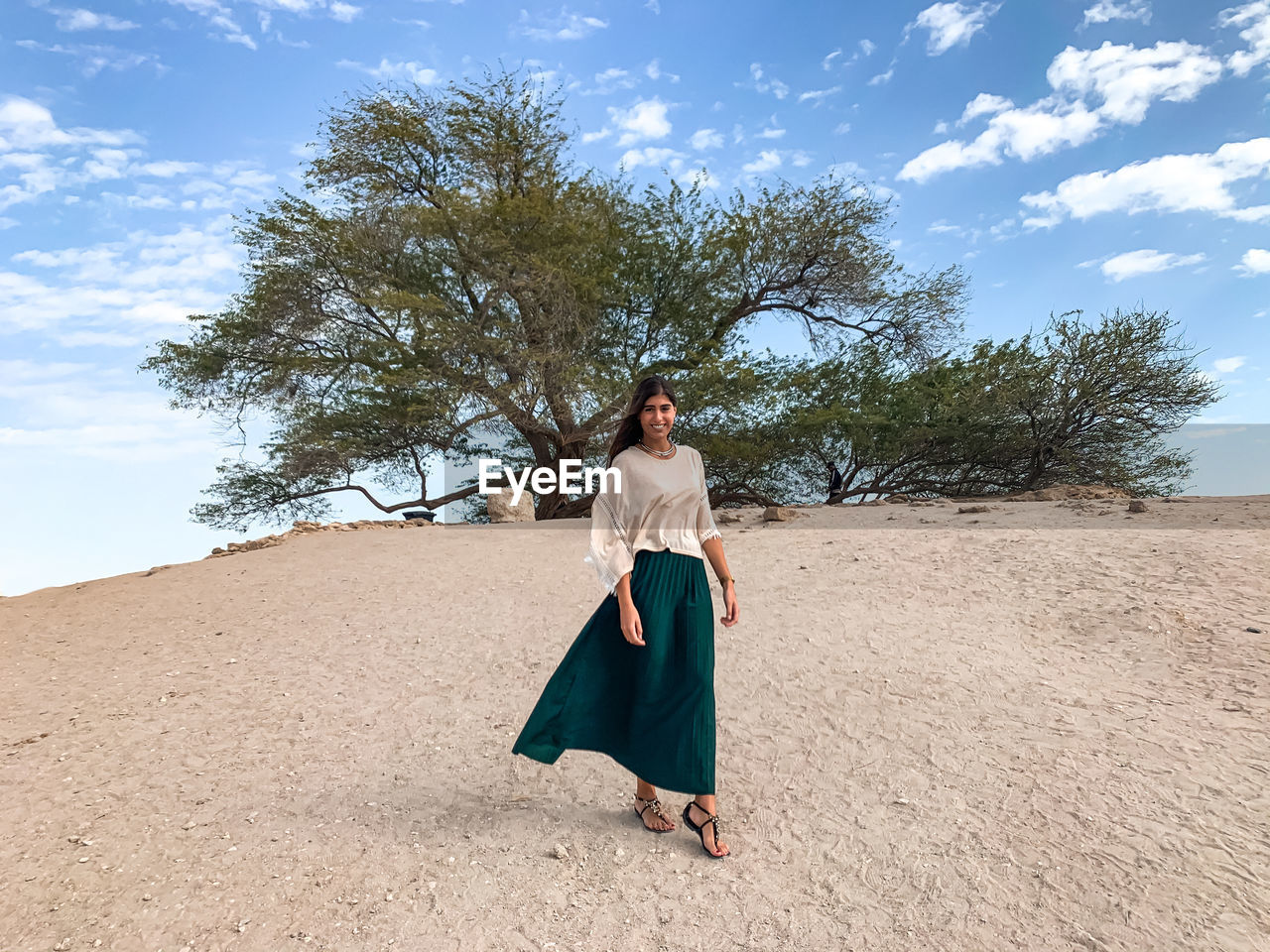 Full length of woman standing by tree on the desert sand against sky