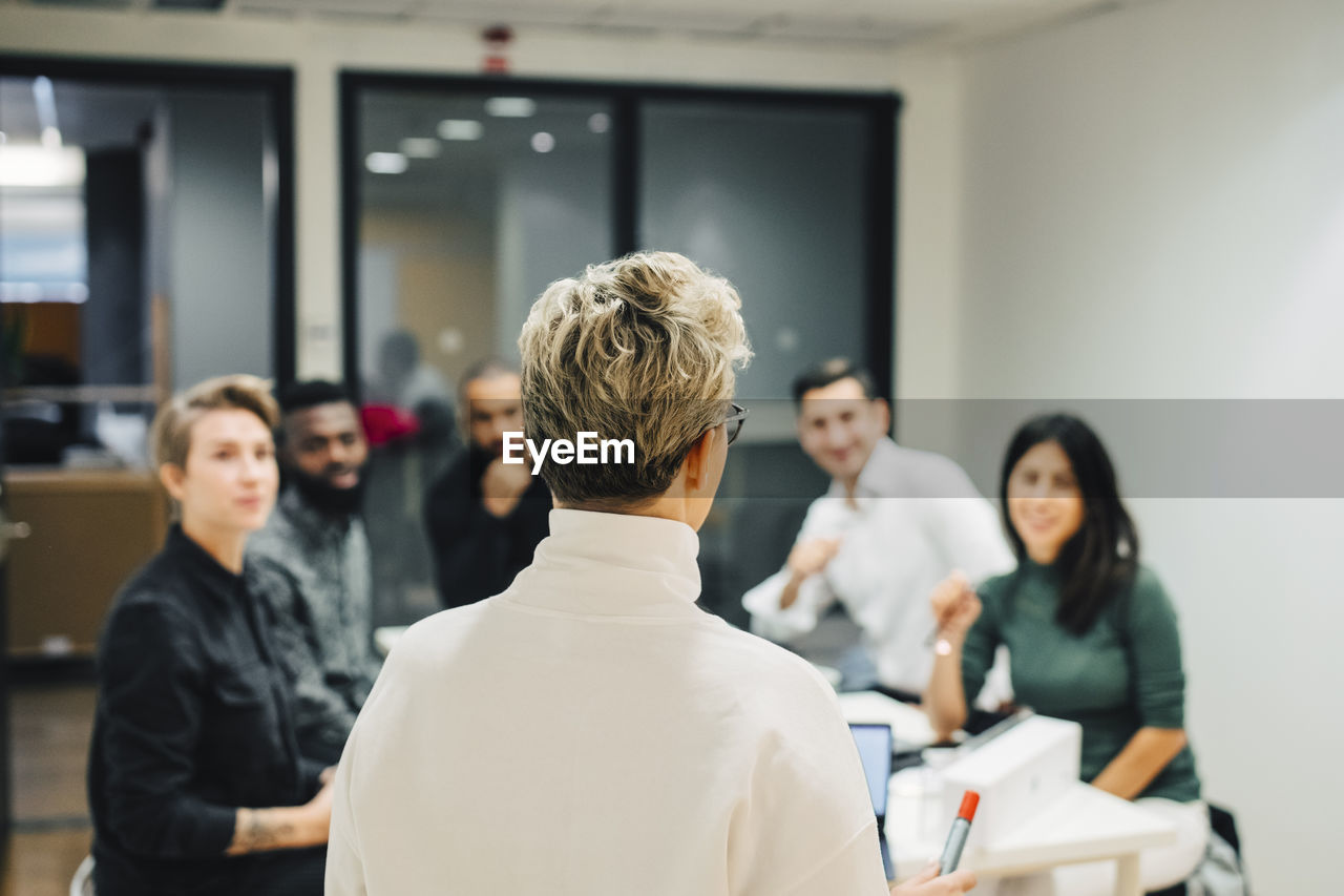 Businesswoman discussing with colleagues in board room at office