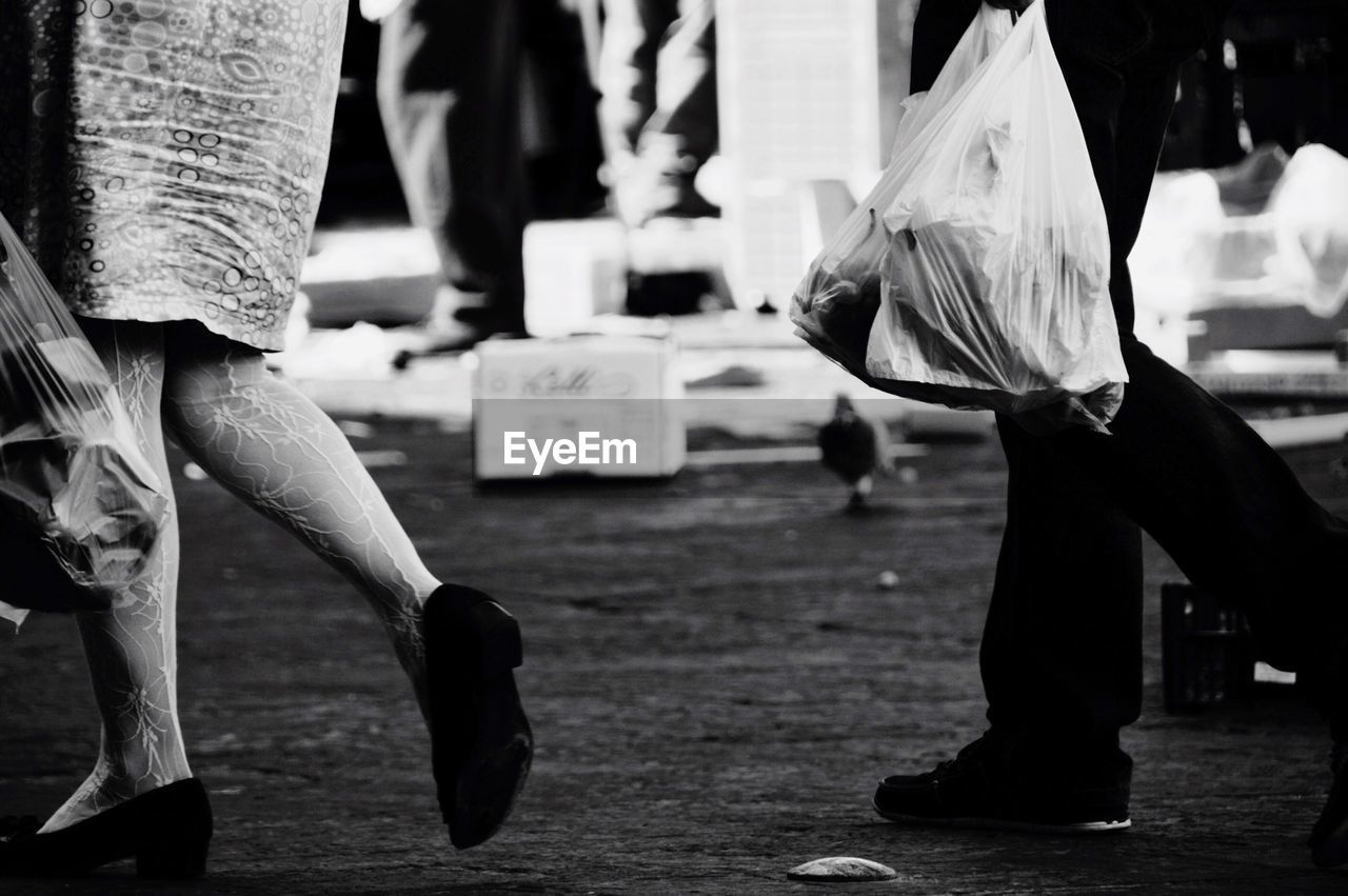 Low section of people carrying plastic bags on road