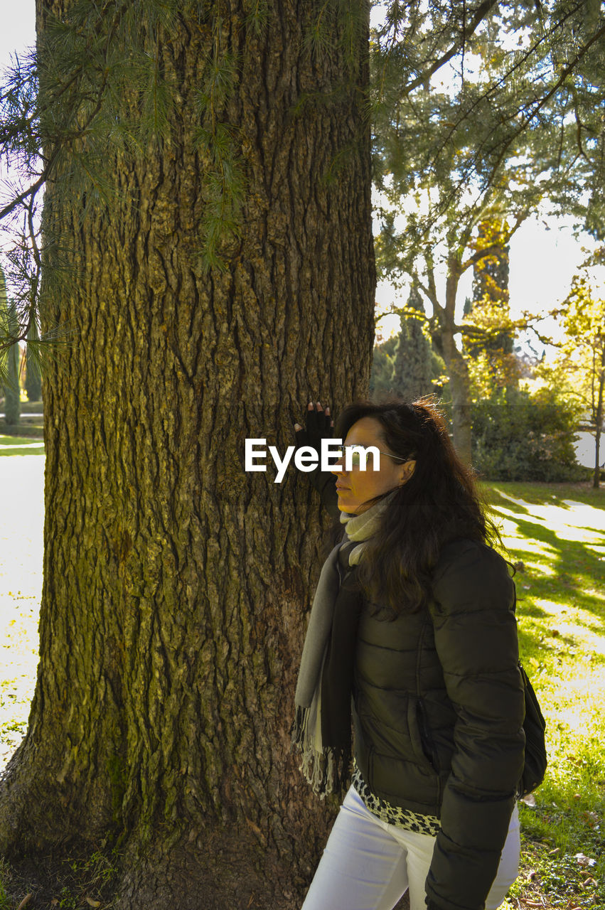 Woman in warm clothing standing by tree at park