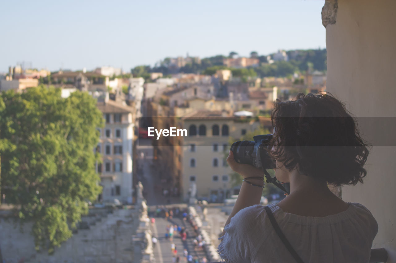 Rear view of woman photographing cityscape