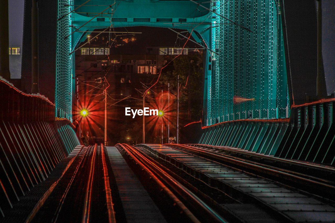 Railroad tracks in illuminated city at night