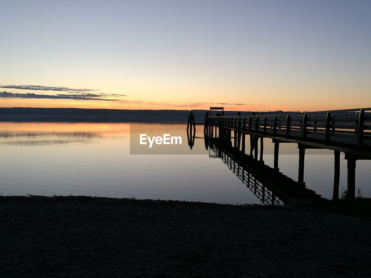 Pier over lake against sky during sunset