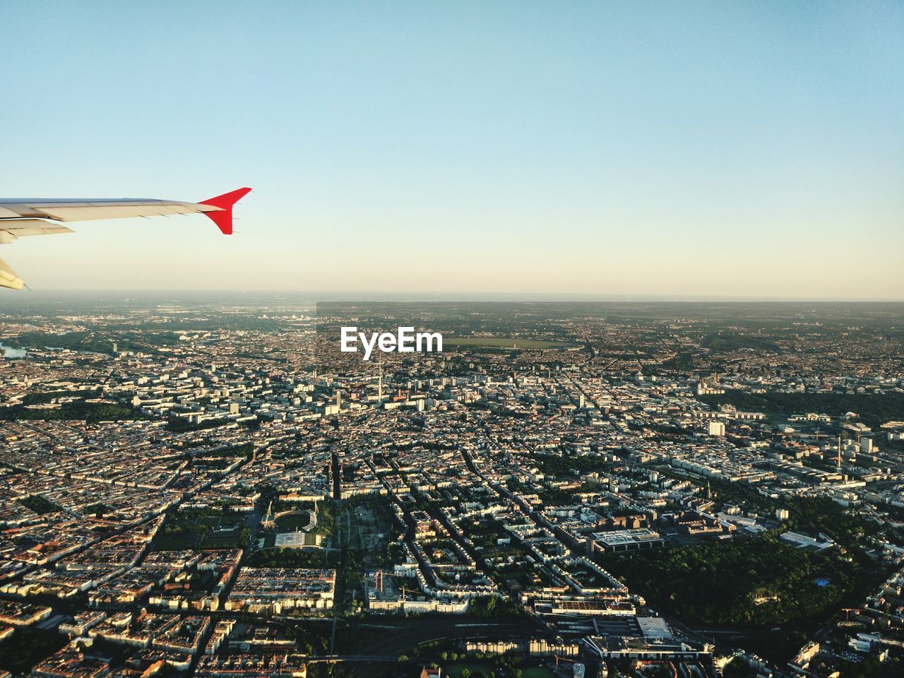 Cropped image of airplane flying over cityscape against sky