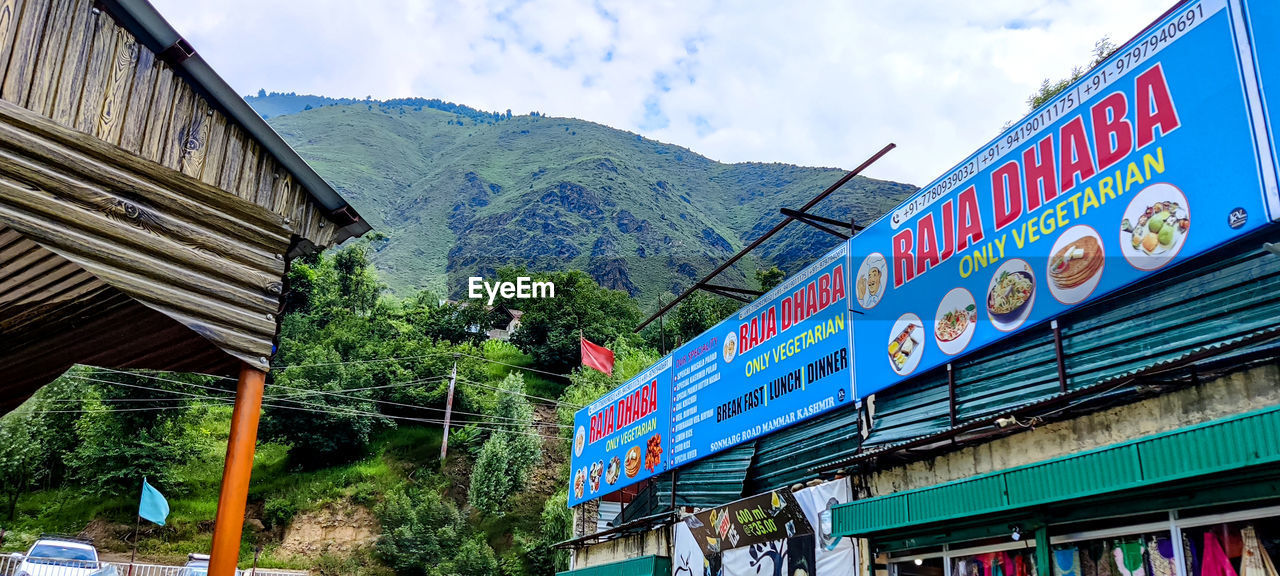 LOW ANGLE VIEW OF TEXT ON BUILDING AGAINST CLOUDY SKY