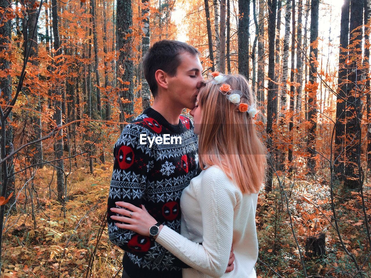 YOUNG COUPLE STANDING IN FOREST