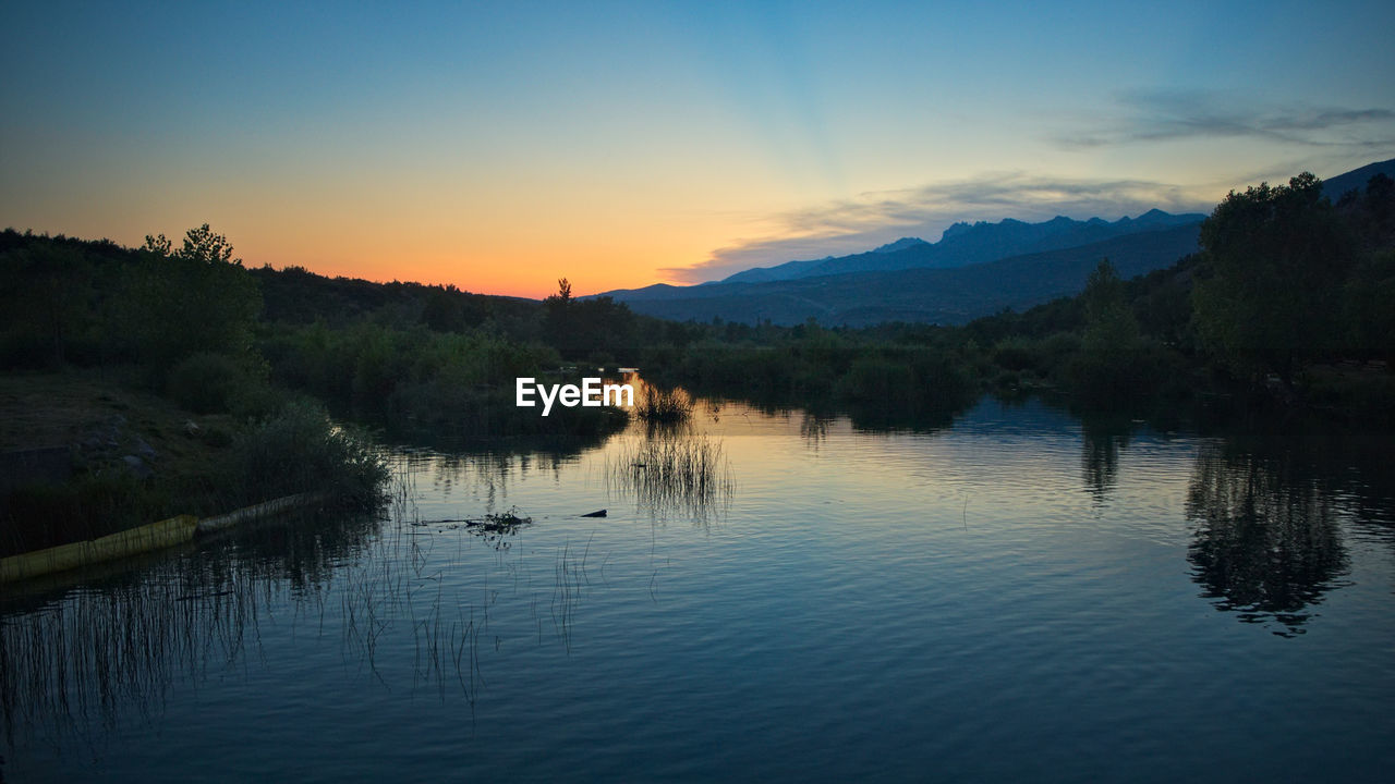 Scenic view of lake against sky at sunset